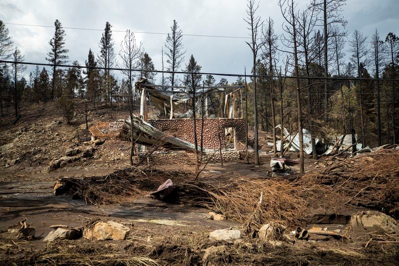 The remains of a house destroyed by the South Fork Fire are pictured among the effects of flash floods in the mountain village of Ruidoso, N.M., Saturday, June 22, 2024. (AP Photo/Andres Leighton)