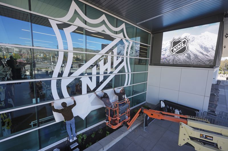 FILE - Workers put up signs celebrating the sale of the Arizona Coyotes and its accompanying relocation to Salt Lake City, at the Delta Center on Thursday, April 18, 2024, in Salt Lake City. (AP Photo/Rick Bowmer, File)