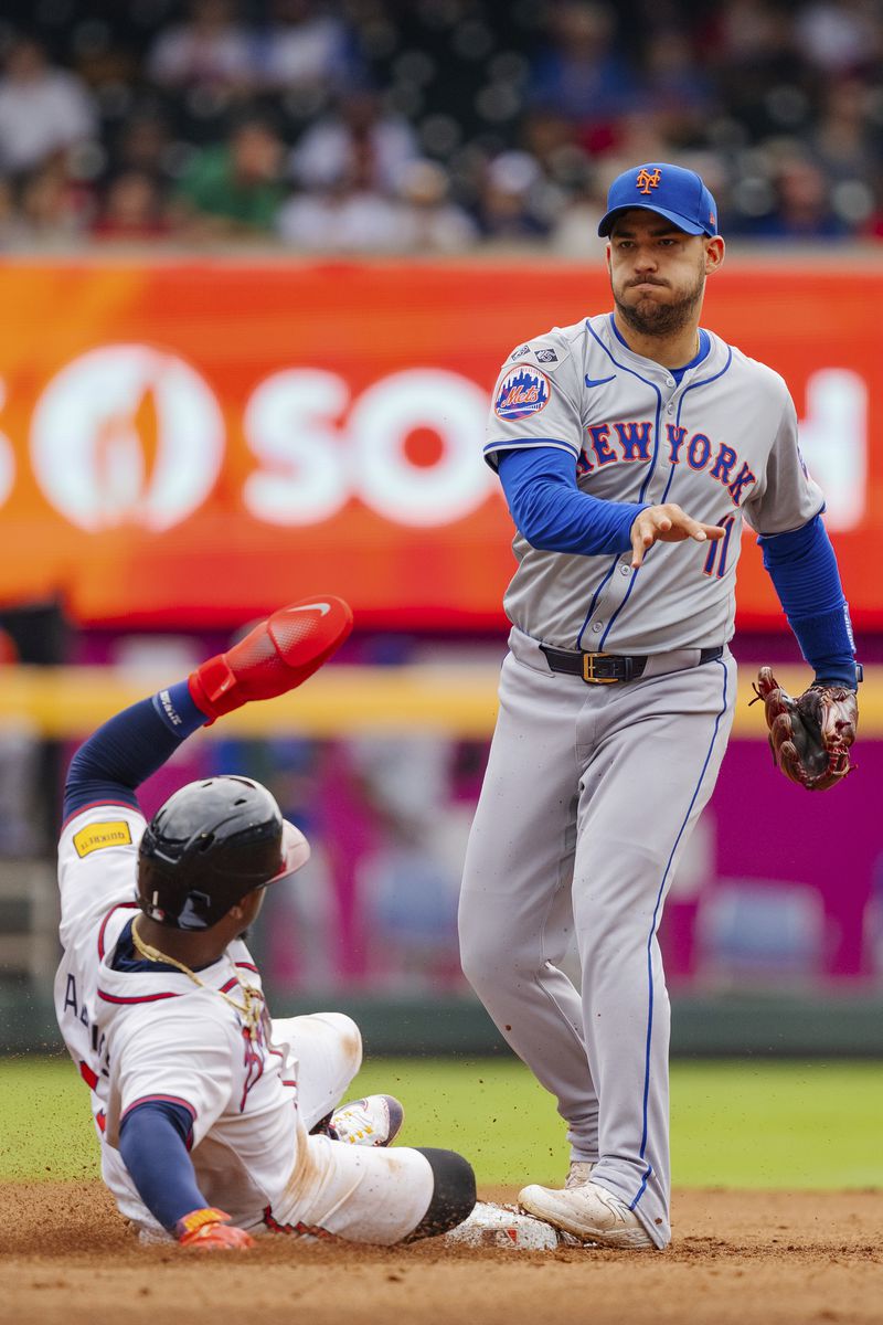 New York Mets second baseman Jose Iglesias, right, tags second base and throws to first before Atlanta Braves' Ozzie Albies, left, can slide into the bag in the fifth inning of a baseball game, Monday, Sept. 30, 2024, in Atlanta. (AP Photo/Jason Allen)