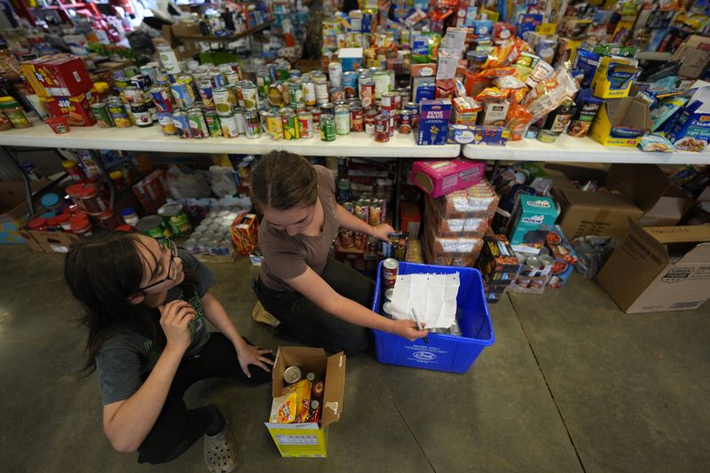 Volunteers gather food for families at the volunteer fire station in the aftermath of Hurricane Helene, Thursday, Oct. 3, 2024, in Pensacola, N.C. (AP Photo/Mike Stewart)