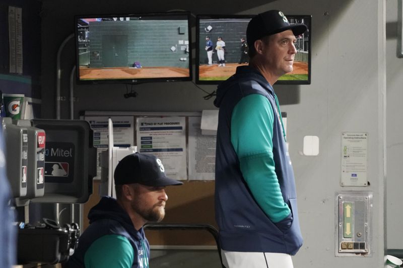 FILE - Seattle Mariners' Dan Wilson, right, stands in the dugout with acting third-base coach Tony Arnerich, left, during a baseball game against the Texas Rangers, Thursday, April 21, 2022, in Seattle. (AP Photo/Ted S. Warren, File)