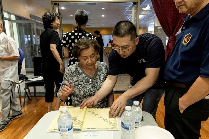 Cizhuo Cheng, field manager for One APIA Nevada, reviews a sample ballot with Sue Deng during the annual Dragon Boat Festival in Las Vegas on Wednesday, June 5, 2024. (Christopher Lomahquahu/News21 via AP)