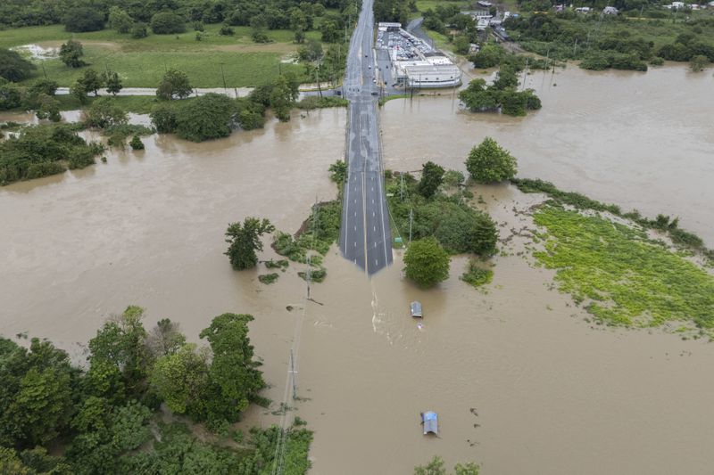 La Plata river floods a road after Tropical Storm Ernesto passed through Toa Baja, Puerto Rico, Wednesday, Aug. 14, 2024. (AP Photo/Alejandro Granadillo)