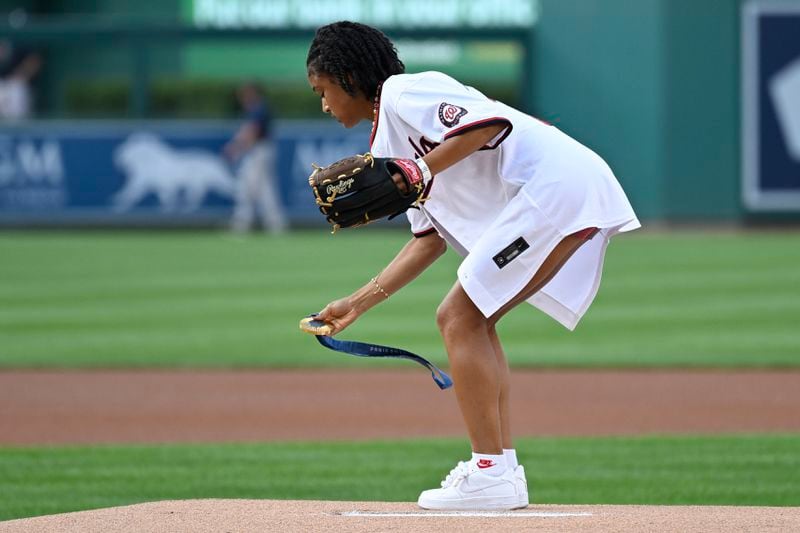 U.S. Olympic women's soccer team member Croix Bethune lays down her gold medal from the 2024 Paris Olympics on the pitcher's mound so she can throw the opening pitch before a baseball game between the Washington Nationals and New York Yankees, Wednesday, Aug. 28, 2024, in Washington. (AP Photo/John McDonnell)