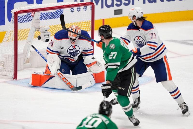 Dallas Stars left wing Mason Marchment (27) scores against Edmonton Oilers goaltender Stuart Skinner (74) as Oilers' Vincent Desharnais (73) looks on during the third period in Game 2 of the Western Conference finals in the NHL hockey Stanley Cup playoffs Saturday, May 25, 2024, in Dallas. (AP Photo/Tony Gutierrez)