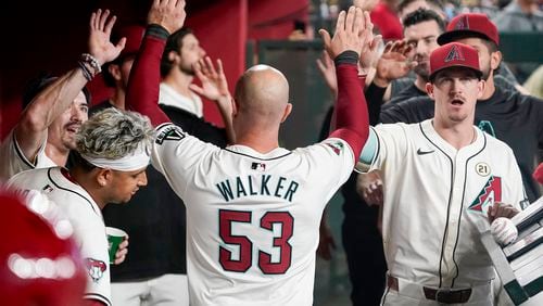 Arizona Diamondbacks' Christian Walker gets high fives from teammates after scoring their second run against the Milwaukee Brewers during the first inning of a baseball game, Sunday, Sept. 15, 2024, in Phoenix. (AP Photo/Darryl Webb)