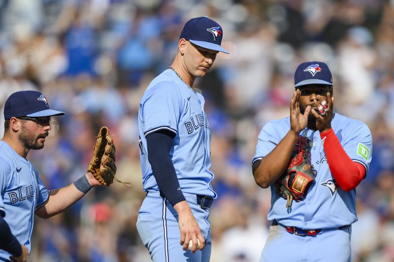 Toronto Blue Jays first base Vladimir Guerrero Jr. and outfielder Davis Schneider congratulate pitcher Bowden Francis after nearly pitching a no-hitter against the Los Angeles Angels during the ninth inning of a baseball game in Toronto, Saturday, Aug. 24, 2024. (Christopher Katsarov/The Canadian Press via AP)