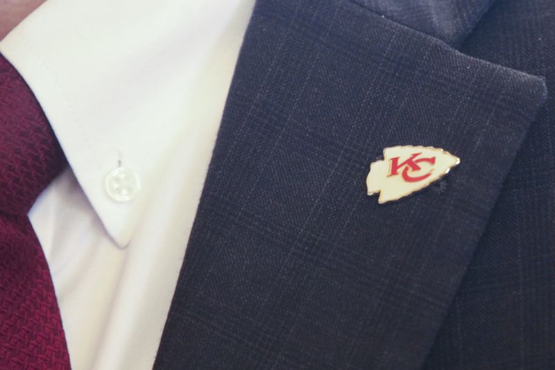 Former Kansas state Rep. Fred Patton, R-Topeka, wears a Kansas City Chiefs pin on the lapel of his suit jacket ahead of a legislative hearing on a proposal to allow Kansas to issue bonds to help finance a new stadium for the professional football team in Kansas, Monday, June 17, 2024, at the Statehouse in Topeka, Kan. Patton represents Scoop and Score, a nonprofit backing the plan, and he is among nearly three dozen lobbyists working for it. (AP Photo/John Hanna)