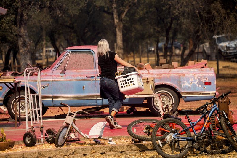 Cindy Miller moves belongings from her home as the Grubbs Fire burns in the Palermo community of Butte County, Calif., on Wednesday, July 3, 2024. (AP Photo/Noah Berger)