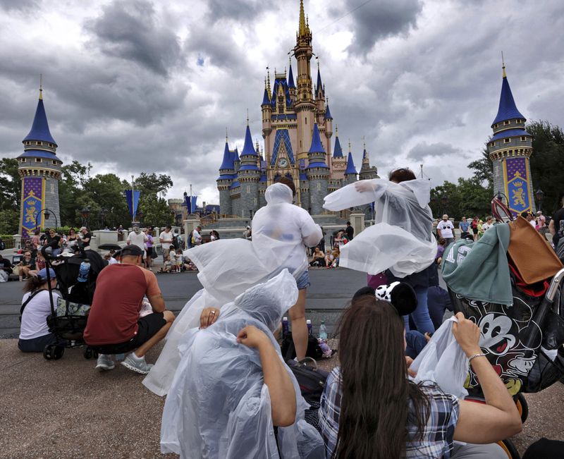 Guests at the Magic Kingdom break out ponchos at Cinderella Castle as bands of weather from Hurricane Helene move through Walt Disney World in Bay Lake, Fla., Thursday, Sept. 26, 2024. All four of Disney's Florida theme parks remained open Thursday as the storm passed to the west in the Gulf of Mexico. (Joe Burbank/Orlando Sentinel via AP)