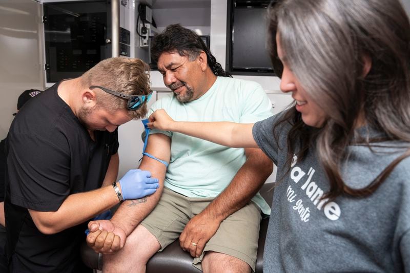 Michael Dennis, left, 25, a second-year Campbell Medical Student, and Genesis Garcia, right, 22, an NC FIELD intern, draw blood from Sabino Reyes, a farmworker, at a mobile health clinic organized by NC FIELD outside María, Reina de las Américas Catholic Church in Mt. Olive, N.C., on Wednesday, June 19, 2024. The mobile clinic is adapted to treat rural patients, many of them agricultural workers, who often work during normal office hours, lack health insurance and face language barriers. (Angelica Edwards/Enlace Latino NC, CatchLight Local via AP)