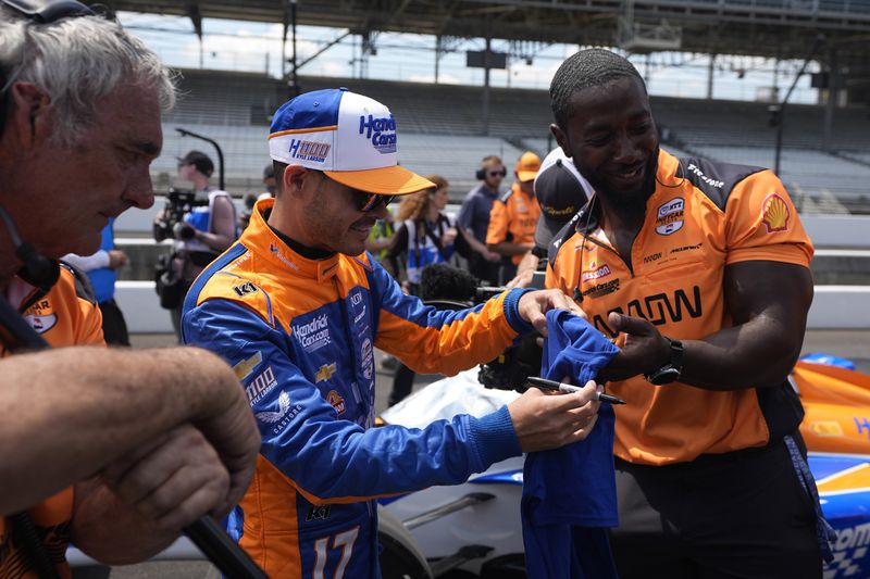 Kyle Larson autographs a shirt during qualifications for the Indianapolis 500 auto race at Indianapolis Motor Speedway, Sunday, May 19, 2024, in Indianapolis. (AP Photo/Darron Cummings)