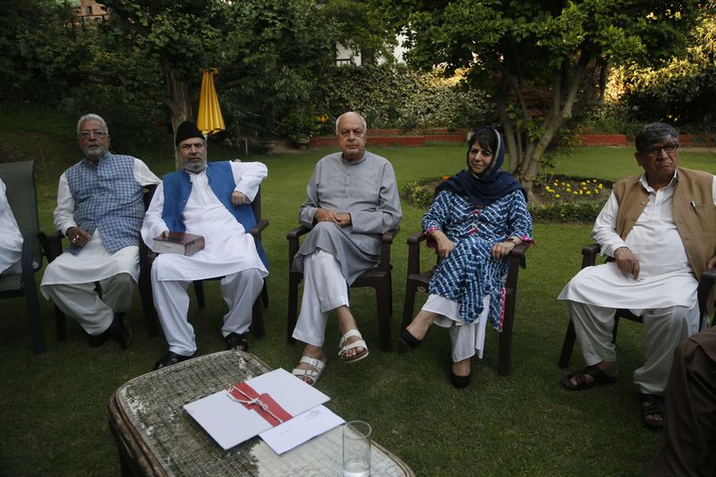 National Conference (NC) President Farooq Abdullah, center, Peoples Democratic Party (PDP) leader Mehbooba Mufti, second right, and other leaders sit during an all parties meeting on restoration of the special status that was stripped last year from Indian-administered Kashmir, in Srinagar, India. (AP Photo/Mukhtar Khan, File)