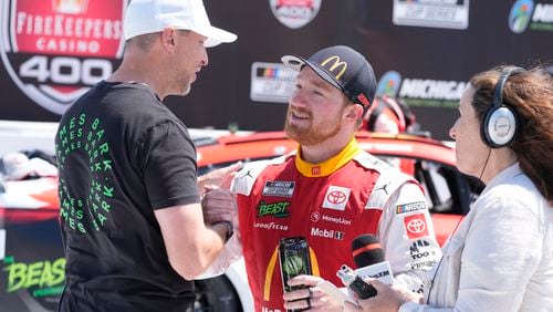 Tyler Reddick is greeted by Denny Hamlin after winning a NASCAR Cup Series auto race at Michigan International Speedway, Monday, Aug. 19, 2024, in Brooklyn, Mich. (AP Photo/Carlos Osorio)