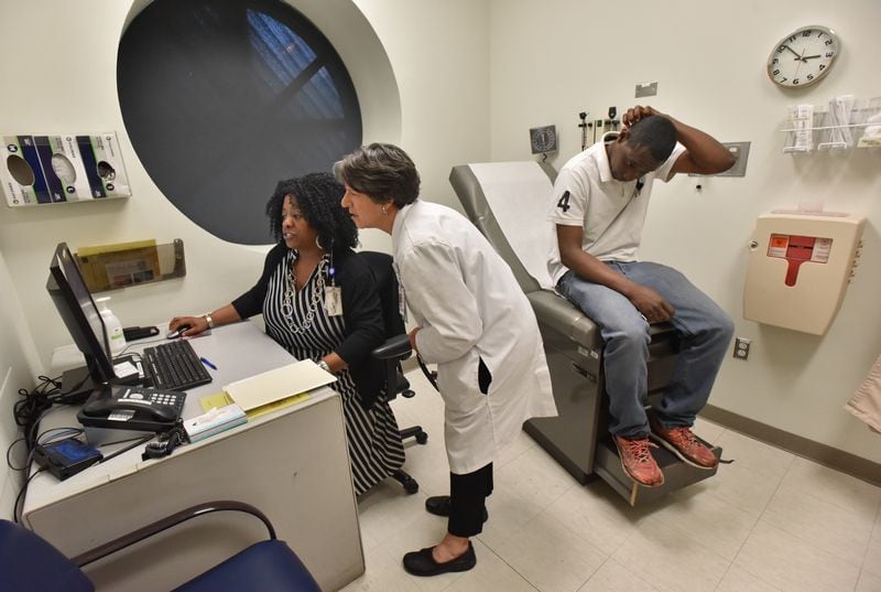 April 17, 2019 Atlanta - Karen Sutton (left), Licensed Clinical Social Worker (LCSW), and Dr. Claudia Vellozzi (center), medical director Chronic Care Clinic, confer as they look medical files of Alex Harris (right), who is a Chronic Care Clinic program participant, at Grady Memorial Hospital's Chronic Care Clinic in Atlanta on Wednesday, April 17, 2019. The Chronic Care Clinic is unique in that it's got not just a doctor and a nurse and assistants, but community health workers who get deeply involved in the patient's situation, a social worker who hooks them up with resources, a behavioral health clinician who addresses addiction and mental health issues, and a highly credentialed pharmacist. HYOSUB SHIN / HSHIN@AJC.COM
