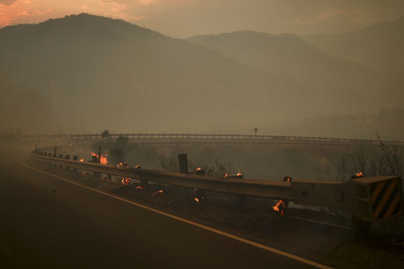 Wood posts along a railing on the side of a road smolders after the Line Fire swept through Saturday, Sept. 7, 2024, near Running Springs, Calif. (AP Photo/Eric Thayer)