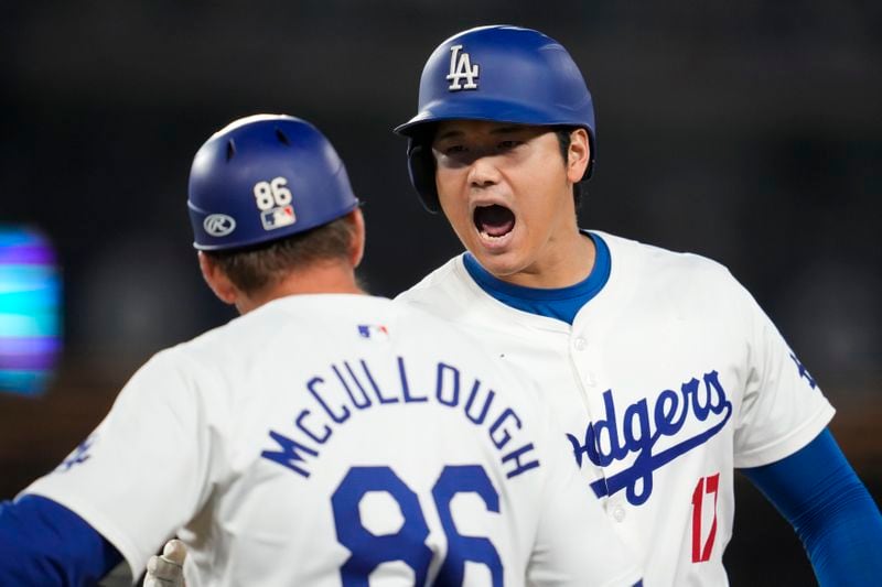 Los Angeles Dodgers designated hitter Shohei Ohtani (17) celebrates with first base coach Clayton McCullough (86) after he singled during the sixth inning of a baseball game against the San Diego Padres in Los Angeles, Wednesday, Sept. 25, 2024. Will Smith scored. (AP Photo/Ashley Landis)