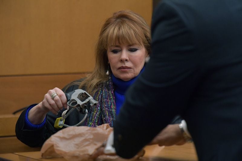 Dani Jo Carter, a close friend of the McIvers and the driver of the SUV on the night that Diane McIver was fatally shot by her husband, holds the gun to demonstrate in front of the jury during Day 7 of the Tex McIver murder trial in Fulton County Superior Court in Atlanta on Wednesday, March 21, 2018. (HYOSUB SHIN / HSHIN@AJC.COM)