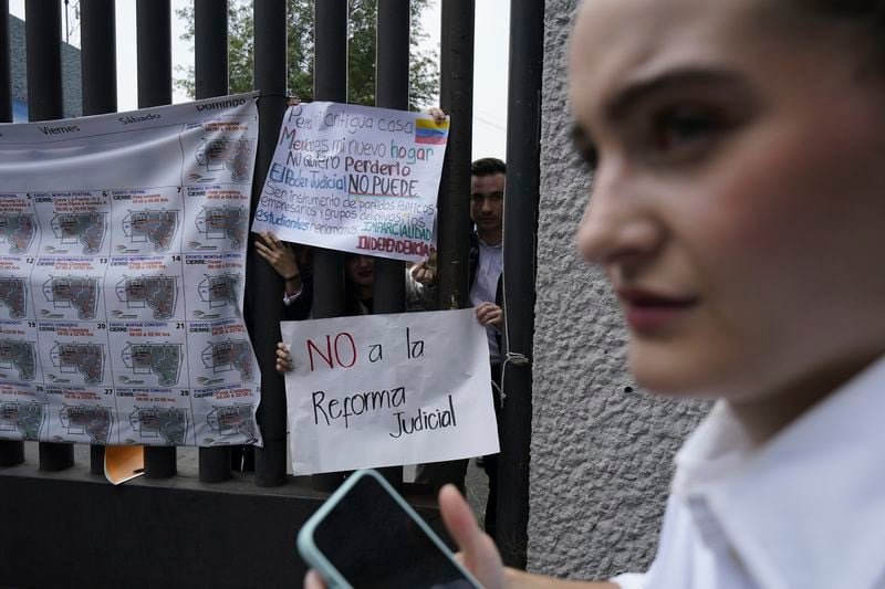 Law students protest against constitutional reform proposals that would make judges stand for election at a sports center where lawmakers are meeting while protesters block Congress in Mexico City, Tuesday, Sept. 3, 2024. The signs read in Spanish: "No to the judicial reform," and "I lost my home. Mexico is my new home. I don't want to lose it. Judicial power cannot be an instrument of political parties, business people, and criminal groups. Students demand impartiality. Independence. (AP Photo/Felix Marquez)